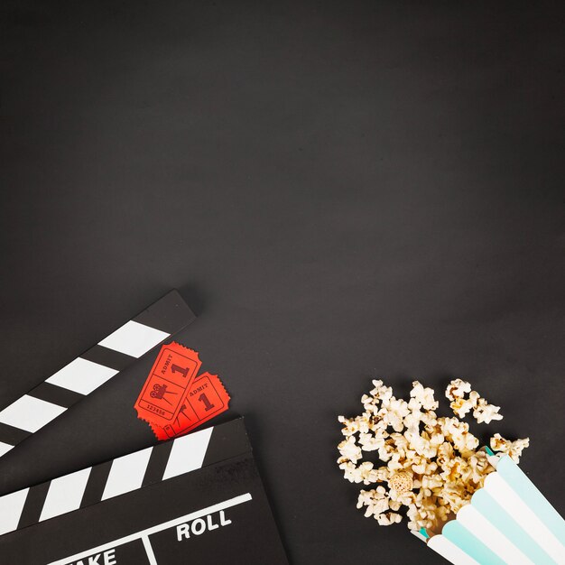 Crop Clapperboard in der Nähe von Tickets und Popcorn