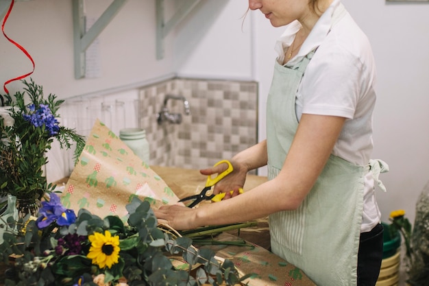 Kostenloses Foto crop floristen schneiden papier für die verpackung bouquet