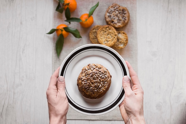 Crop Hände halten Teller mit Brötchen