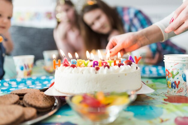 Crop Hände in der Nähe von Kuchen mit Kerzen