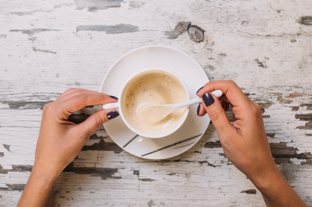 Crop Hände rühren Kaffee