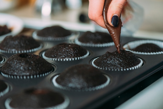 Crop Hand Füllung Muffins mit Sauce