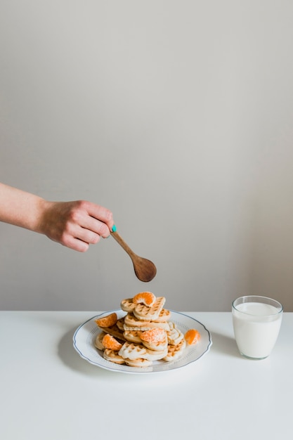 Crop Hand mit Löffel über Waffeln