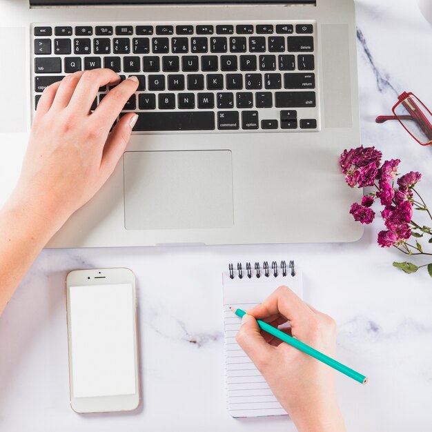 Crop Hand Surfen Laptop und Schreiben in Notebook