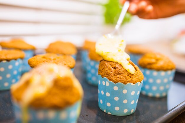 Crop Hand Verbreitung Sauce auf Muffin