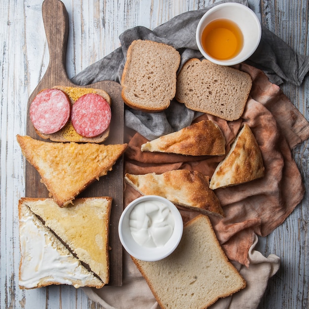 Croutons von oben mit Wurst und Honig und Sauerrahm im Schneidebrett