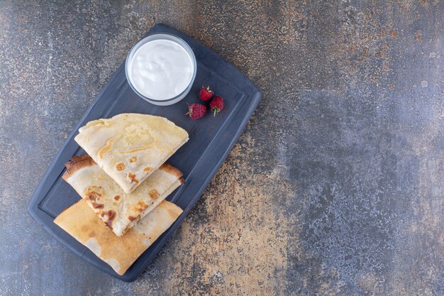 Crpes auf einer schwarzen Platte mit Himbeeren und einer Tasse Milch