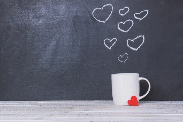 Cup mit einer Tafel hinter mit Herzen gezeichnet