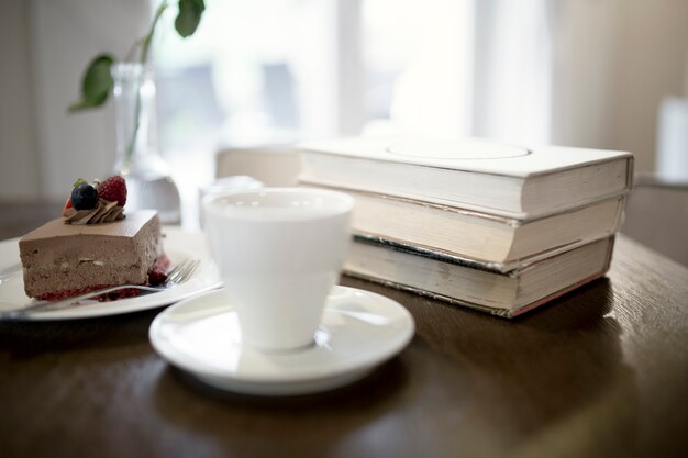 Cup und Dessert in der Nähe von Büchern