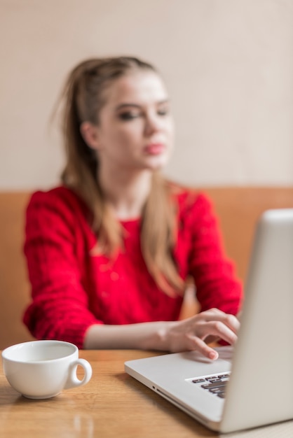 Kostenloses Foto cup und laptop mit unscharfem hintergrund frau