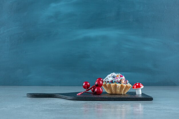 Cupcake mit Süßigkeiten und Weihnachtsschmuck auf einer schwarzen Tafel auf Marmoroberfläche