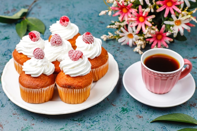 Cupcakes dekorierten schlagsahne und gefrorene himbeeren.