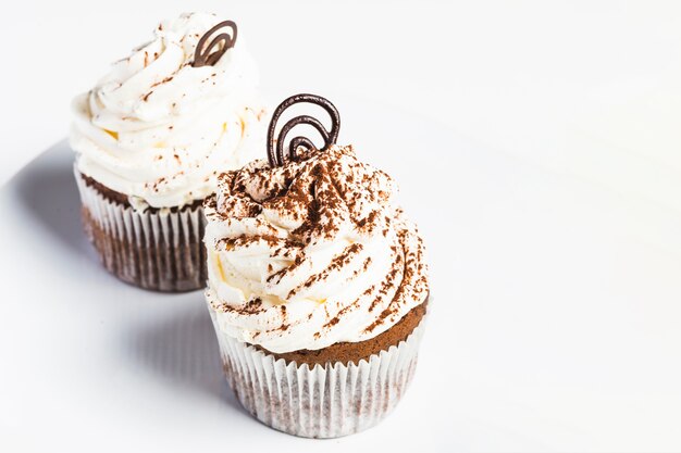 Cupcakes mit der gewirbelten Creme getrennt auf weißem Hintergrund