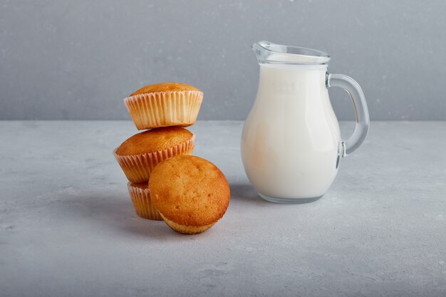 Cupcakes mit einem Glas Milch auf grauem Hintergrund.