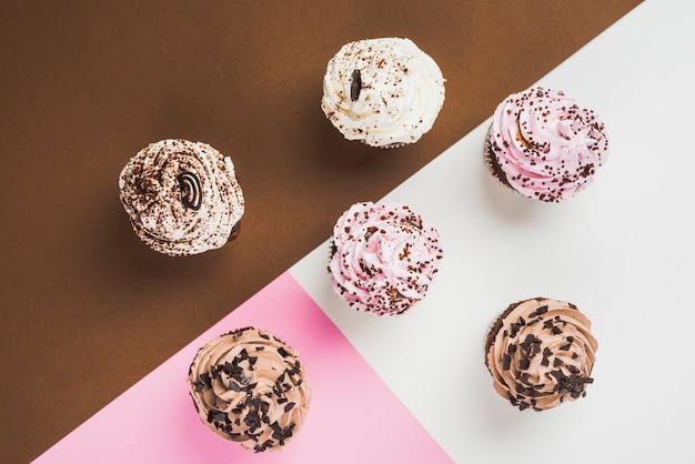 Cupcakes mit verschiedenen Zuckerguss auf mehrfarbigen Hintergrund