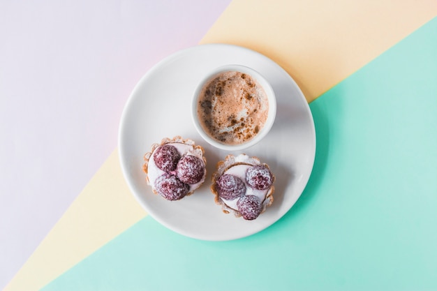 Cupcakes und Kaffee auf tri farbigem Hintergrund