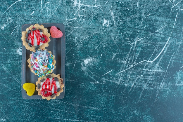 Kostenloses Foto cupcakes und marmeladen gebündelt auf einer platte auf blauem hintergrund. hochwertiges foto