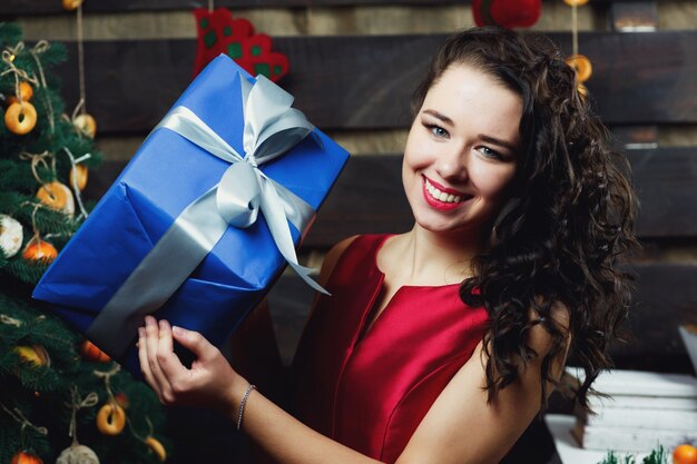 Curly brunette Frau hält blaue Geschenkbox