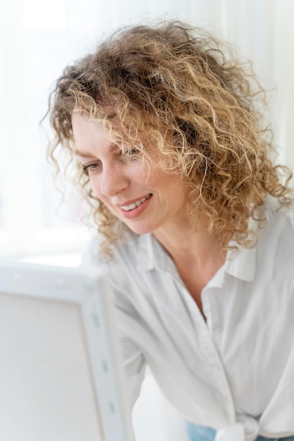 Curly-haired blonde Frau malt zu Hause