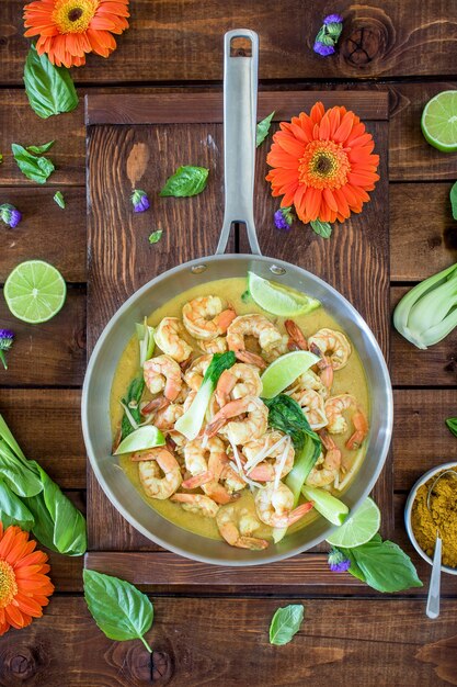 Curry-Garnelensuppe serviert in einem silbernen Topf auf einem braunen Tisch