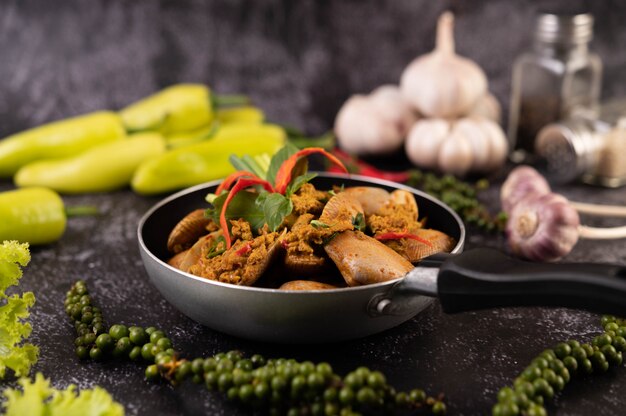 Currypulver auf einer schwarzen Pfanne mit Knoblauch-Chili und Basilikum gebraten.