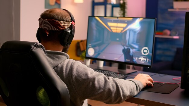 Cyber-Gamer, der Hände und Nacken streckt, bevor er Online-Videospiele mit RGB-Tastatur und -Maus spielt. Spieler, die während des Gaming-Turniers Online-Spiele durchführen