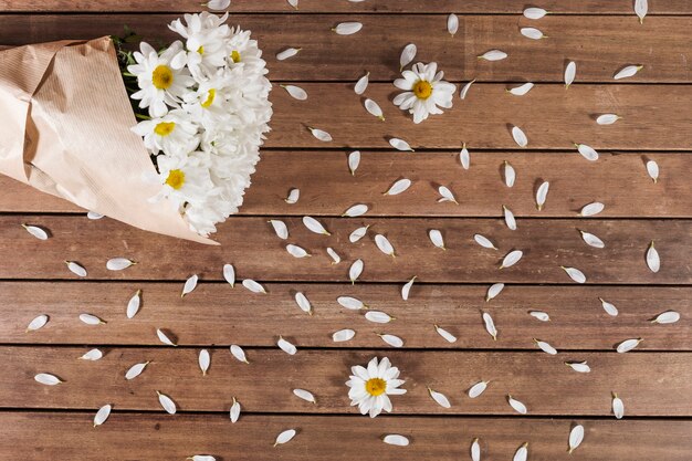 Daisy Bouquet und Blütenblätter auf hölzernen Oberfläche