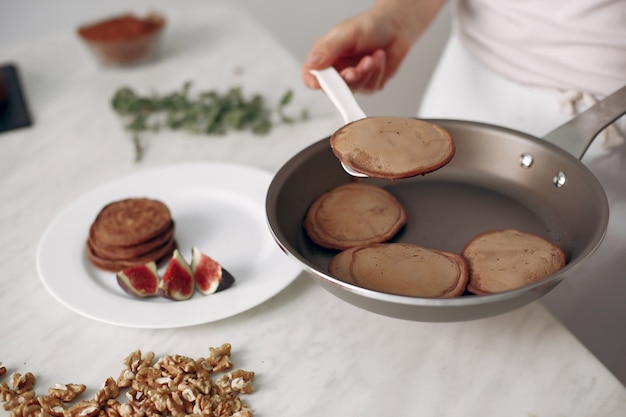 Dame bereitet Dessert vor. Konditor backt Pfannkuchen. Frau hält eine Pfanne in seinen Händen.