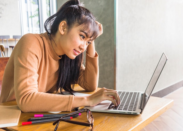 Dame, die bei tisch bei laptop durchstöbert