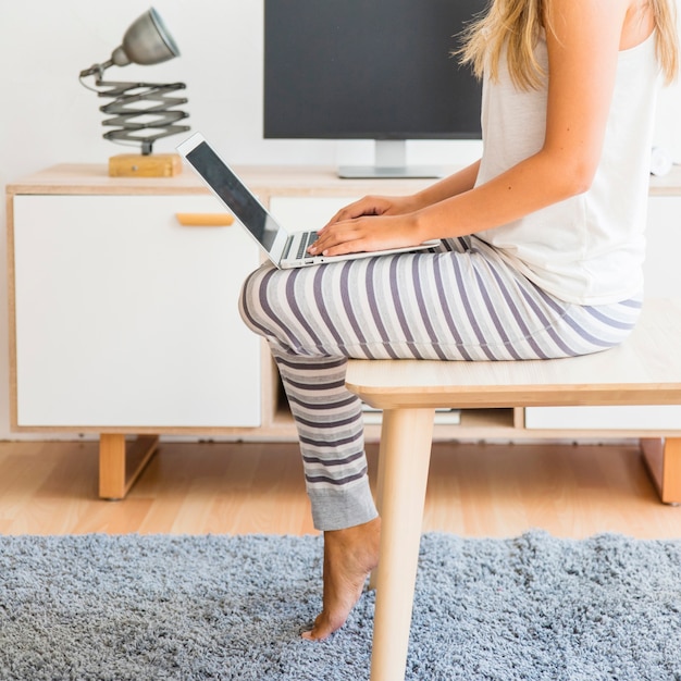 Kostenloses Foto dame, die mit laptop auf beinen sitzt