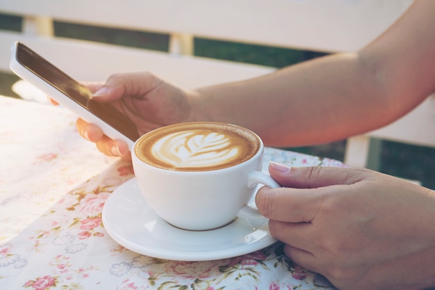 Kostenloses Foto dame, die mobilen weißen trinkenden kaffee verwendet