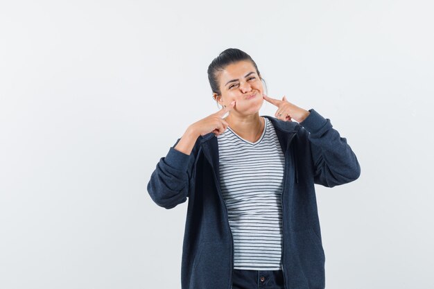 Dame drückt Finger auf geblasene Wangen im T-Shirt