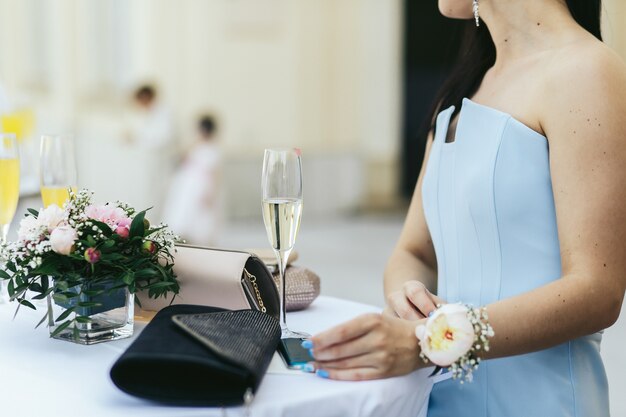 Dame im blauen Kleid mit Blume über ihrem wirst sitzt am Tisch