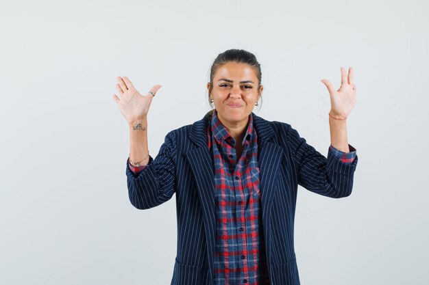 Dame im Hemd, Jacke, die Handflächen in Übergabegeste zeigt und selbstbewusst aussieht, Vorderansicht.