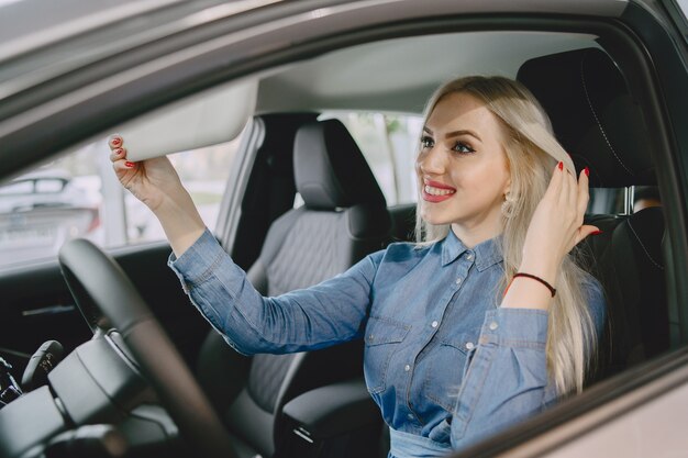 Dame in einem Autosalon. Frau, die das Auto kauft. Elegante Frau in einem blauen Kleid.