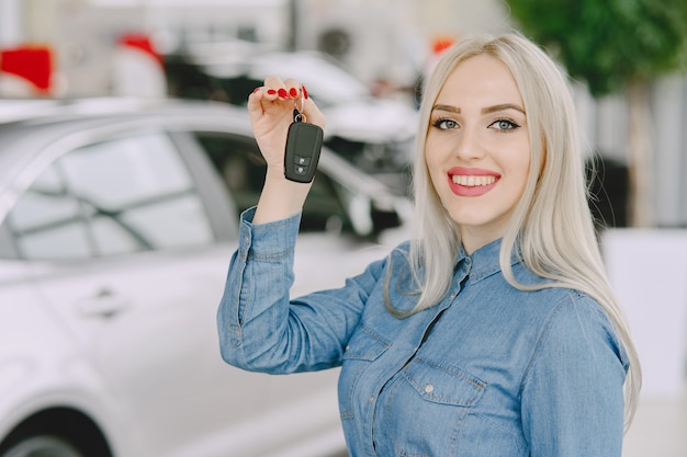 Dame in einem Autosalon. Frau, die das Auto kauft. Elegante Frau in einem blauen Kleid.