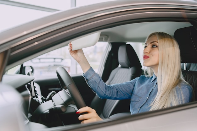 Dame in einem Autosalon. Frau, die das Auto kauft. Elegante Frau in einem blauen Kleid.