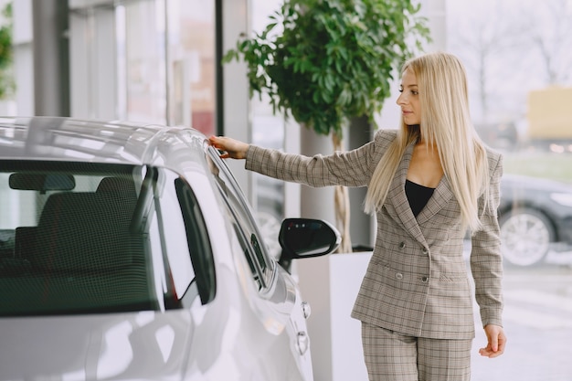 Dame in einem Autosalon. Frau, die das Auto kauft. Elegante Frau in einem braunen Anzug.