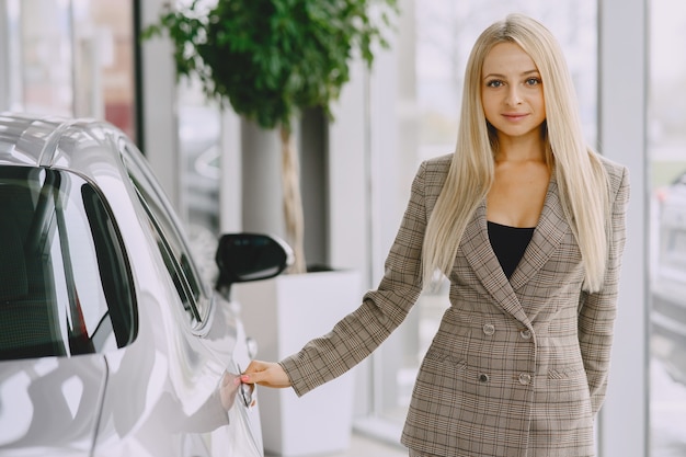 Dame in einem Autosalon. Frau, die das Auto kauft. Elegante Frau in einem braunen Anzug.