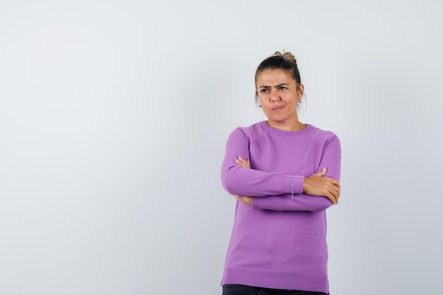 Dame in Wollbluse mit verschränkten Armen und unentschlossenem Blick