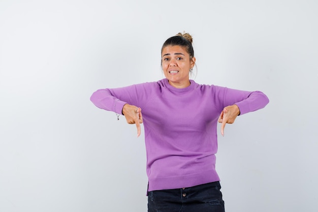 Dame in Wollbluse zeigt nach unten und sieht fröhlich aus looking