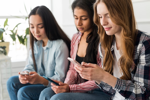 Damen, die Handy sitzen und halten