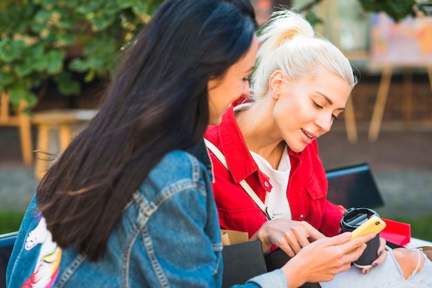 Damen, die Smartphone auf Bank im Park verwenden