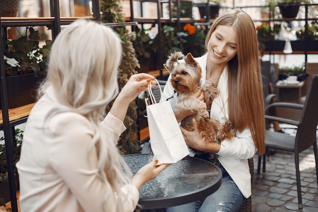 Kostenloses Foto damen im straßencafé. frauen sitzen am tisch. freunde mit einem niedlichen hund.