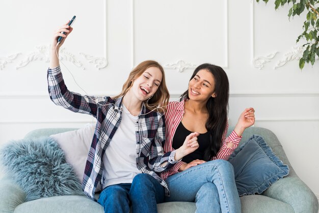 Damen sitzen und hören Musik vom Telefon