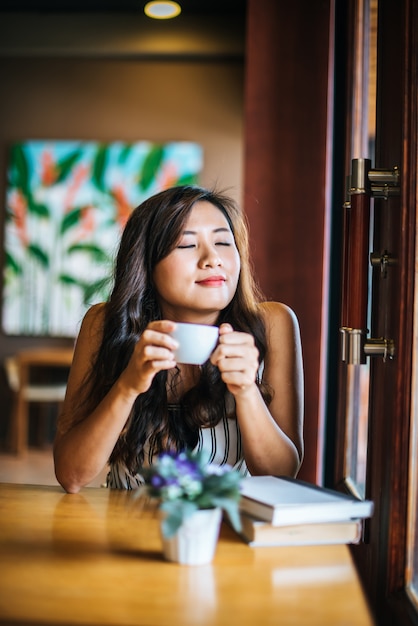 Das asiatische Frauenlächeln des Porträts entspannen sich im Kaffeestubecafé