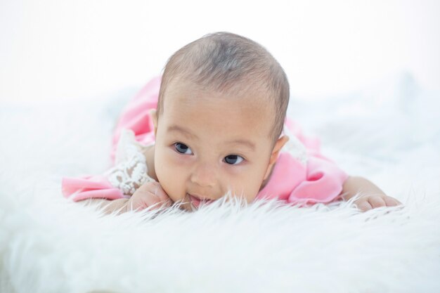 Das Baby liegt auf einem weißen Bett.