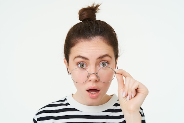 Kostenloses Foto das bild einer frau mit brille sieht überrascht aus, zieht die brille ab, sieht erstaunt aus und sagt: 