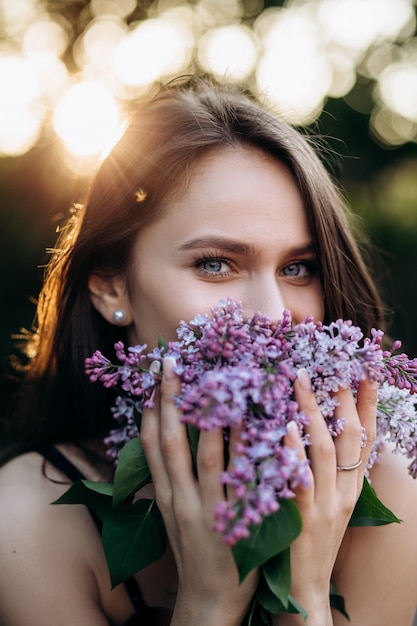 Das charmante Mädchen steht im Park und hält einen Blumenstrauß