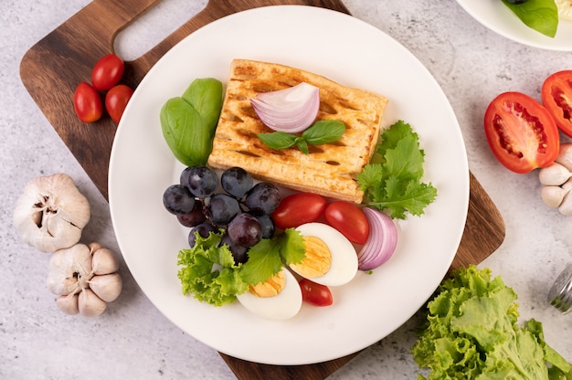 Das Frühstück besteht aus Brot, gekochten Eiern, schwarzem Traubensalatdressing, Tomaten und geschnittenen Zwiebeln.